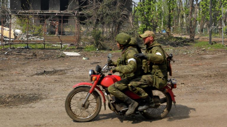 Военнослужащие едут на мотоцикле мимо разрушенных домов в городе Попасная Военнослужащие едут на мотоцикле мимо разрушенных домов в городе Попасная