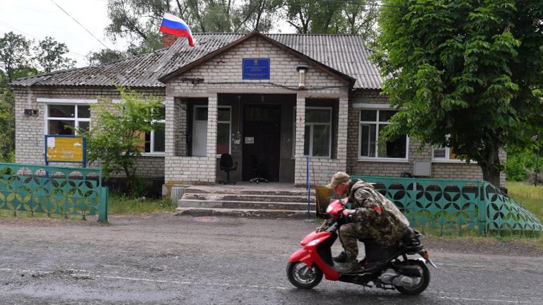 Патрульный народной милиции ЛНР едет мимо бывшего Исполнительного комитета Лиманской городской рады в освобожденном селе Яцковка Патрульный народной милиции ЛНР едет мимо бывшего Исполнительного комитета Лиманской городской рады в освобожденном селе Яцковка