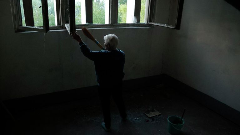 Женщина убирает осколки стекол на лестнице в подъезде жилого дома после обстрела ВСУ жилого сектора в Буденновском районе Донецка