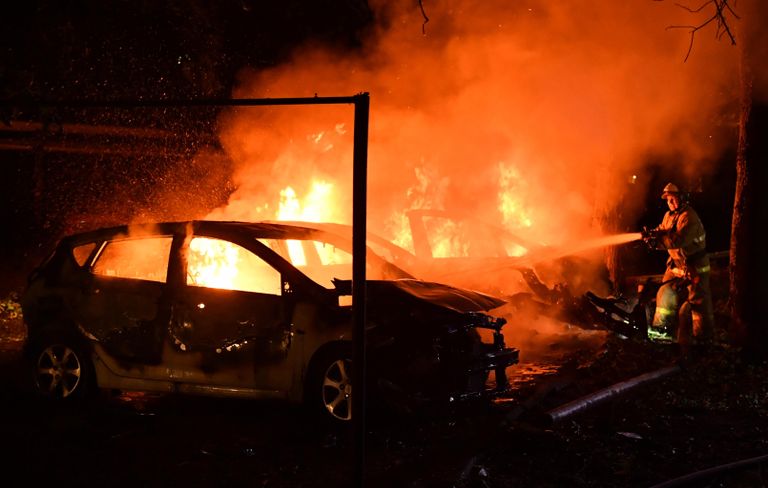 Сотрудник противопожарной службы МЧС ДНР тушит автомобили, сгоревшие в результате обстрела ВСУ в Донецке