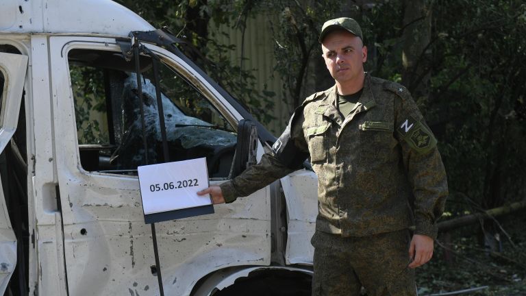 Военнослужащий НМ ДНР у поврежденного автомобиля после обстрелов украинскими войсками в Петровском районе Донецка Военнослужащий НМ ДНР у поврежденного автомобиля после обстрелов украинскими войсками в Петровском районе Донецка