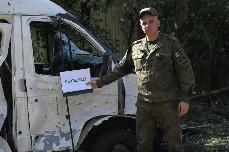 Военнослужащий НМ ДНР у поврежденного автомобиля после обстрелов украинскими войсками в Петровском районе Донецка