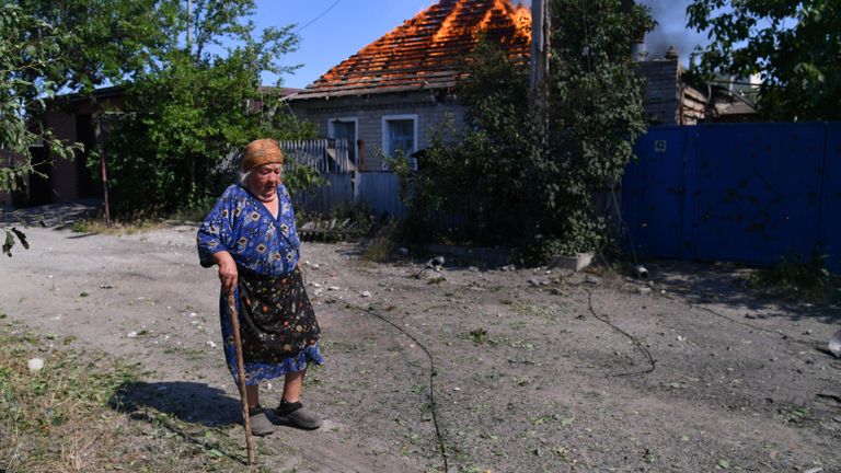 Жительница окраины Северодонецка идет мимо горящего дома, в который попал снаряд при артиллерийском обстреле Жительница окраины Северодонецка идет мимо горящего дома, в который попал снаряд при артиллерийском обстреле