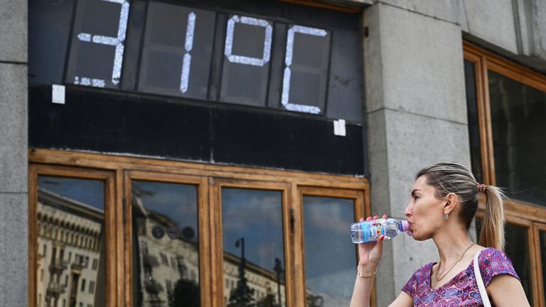 Девушка пьет воду возле здания Центрального телеграфа на Тверской улице в Москве Девушка пьет воду возле здания Центрального телеграфа на Тверской улице в Москве