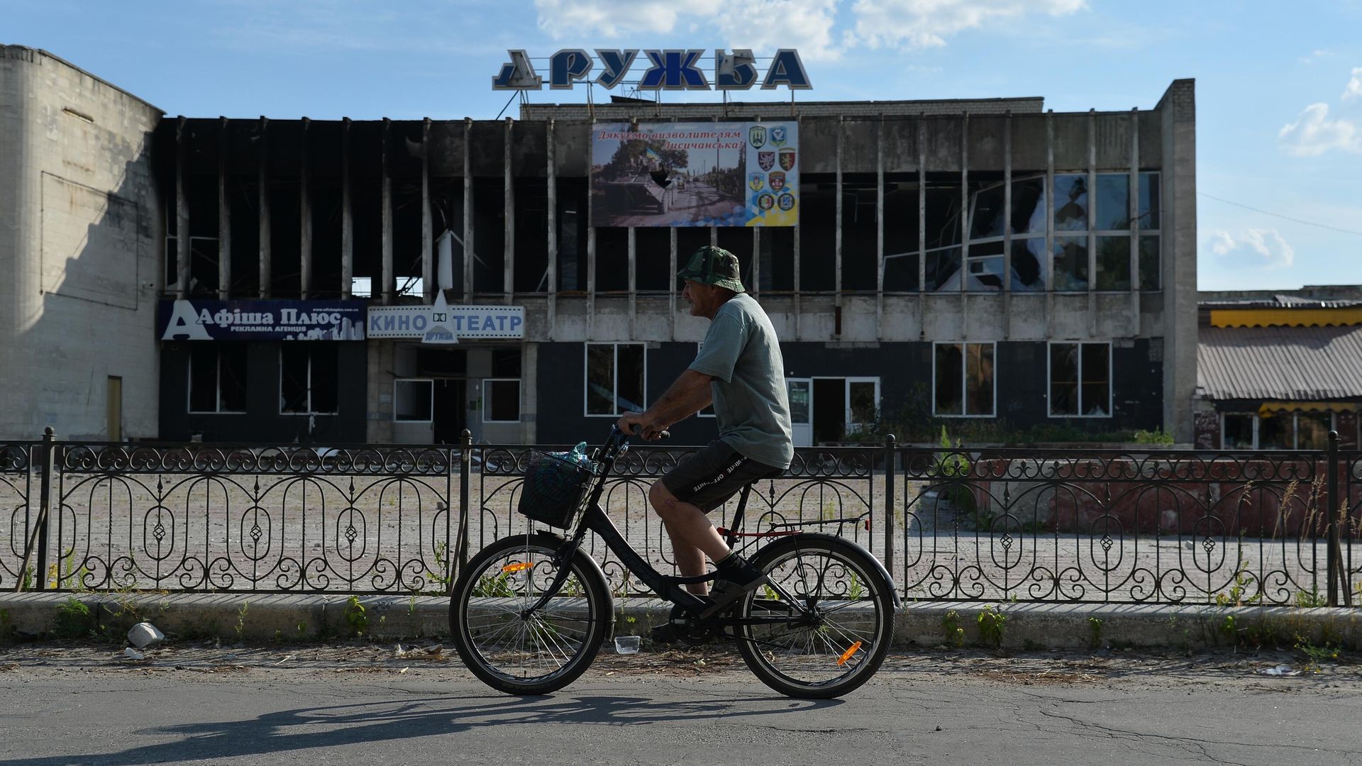 Велосипедист едет мимо разрушенного здания кинотеатра Дружба в Лисичанске Велосипедист едет мимо разрушенного здания кинотеатра Дружба в Лисичанске - РИА Новости, 1920, 07.08.2022