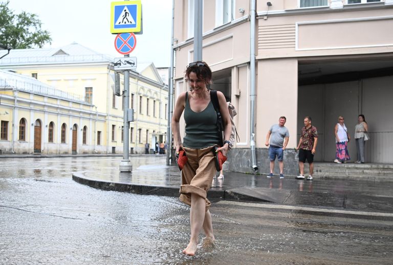 Женщина переходит улицу по лужам в Москве Женщина переходит улицу по лужам в Москве