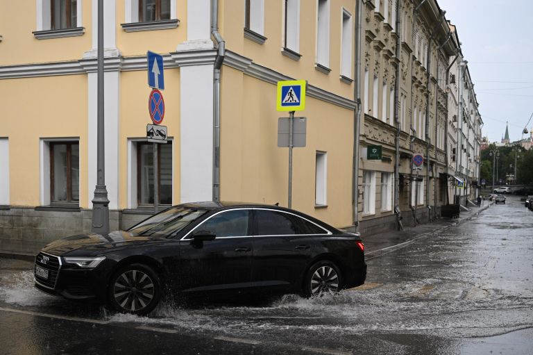 Автомобиль едет по лужам на улице Ленивка в Москве Автомобиль едет по лужам на улице Ленивка в Москве