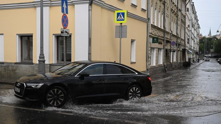 Автомобиль едет по лужам на улице Ленивка в Москве Автомобиль едет по лужам на улице Ленивка в Москве