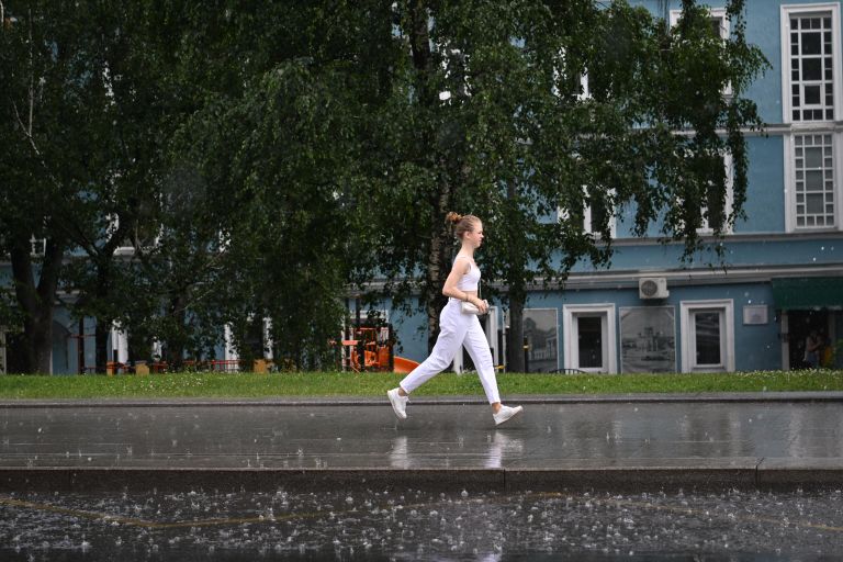 Женщина переходит улицу по лужам в Москве Женщина переходит улицу по лужам в Москве