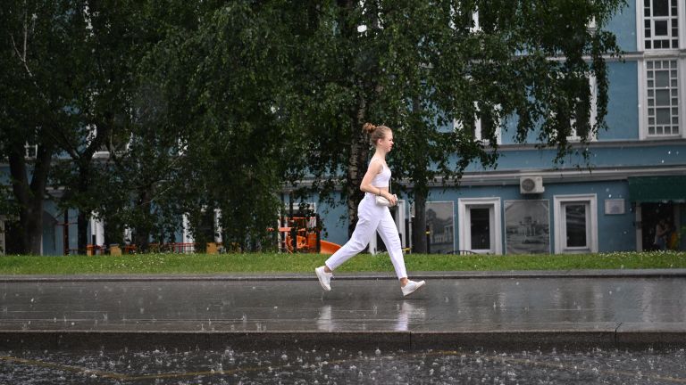 Женщина переходит улицу по лужам в Москве Женщина переходит улицу по лужам в Москве