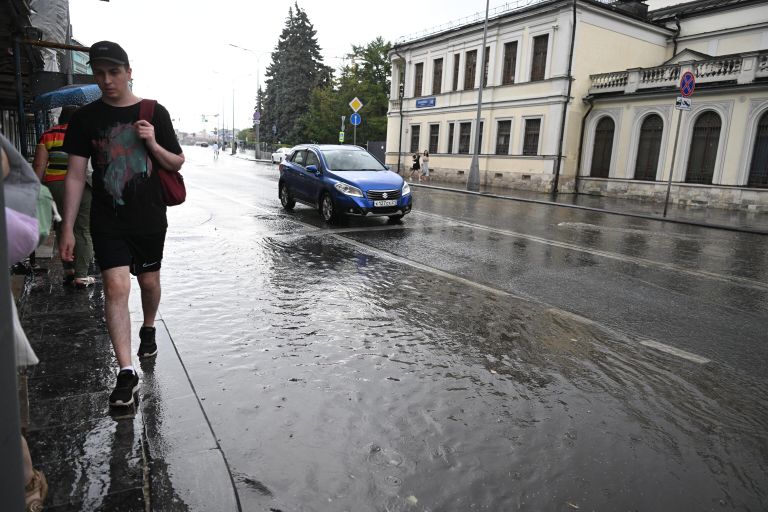 Мужчина идет по лужам на улице Волхонка в Москве Мужчина идет по лужам на улице Волхонка в Москве