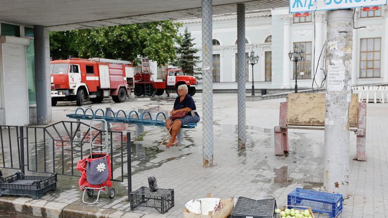 Женщина сидит на остановке общественного транспорта возле здания железнодорожного вокзала в Донецке Женщина сидит на остановке общественного транспорта возле здания железнодорожного вокзала в Донецке