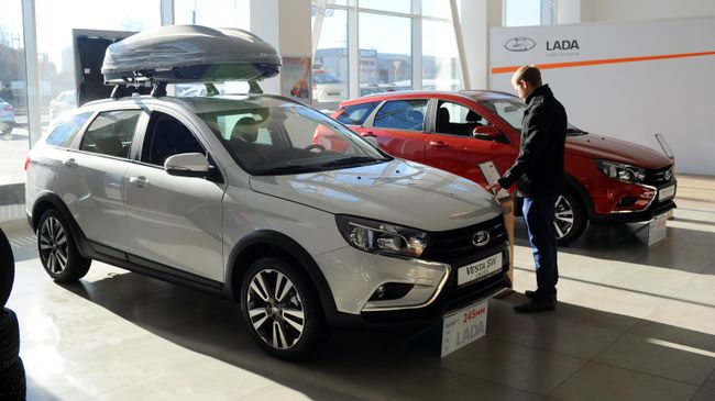 Посетитель рассматривает автомобиль Lada Vesta SW в демонстрационном зале автоцентра
