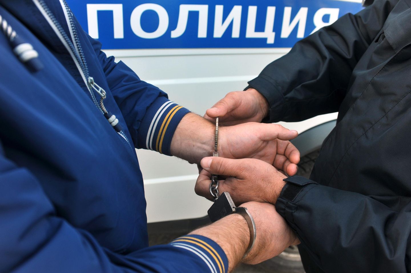 Сотрудник полиции надевает наручники на правонарушителя Сотрудник полиции надевает наручники на правонарушителя