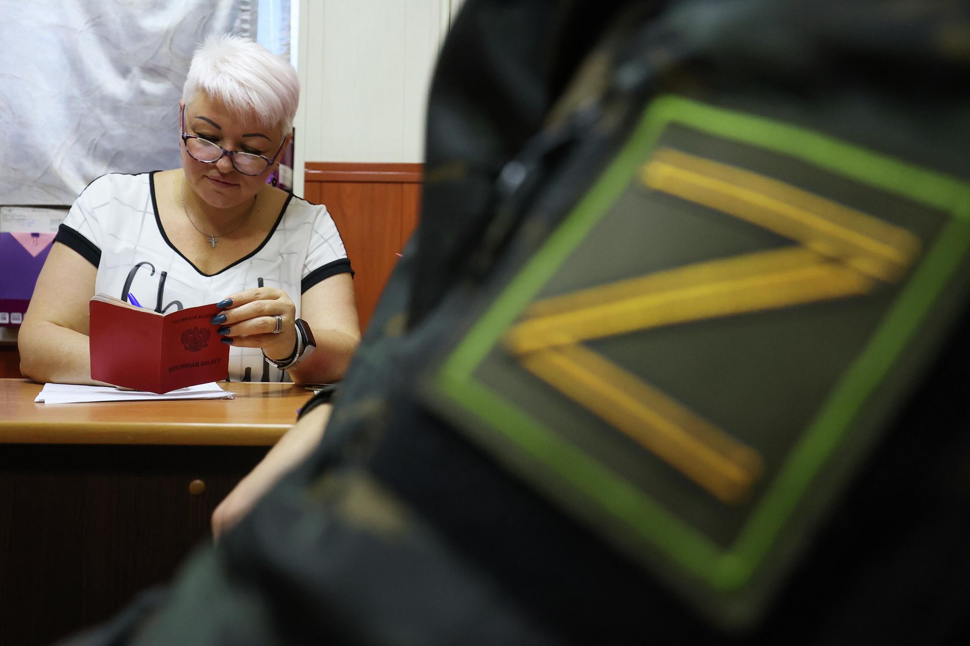 Сотрудница военного комиссариата читает военный билет мужчины, призванного на воинскую службу в ходе частичной мобилизации Сотрудница военного комиссариата читает военный билет мужчины, призванного на воинскую службу в ходе частичной мобилизации - РИА Новости, 1920, 12.10.2022