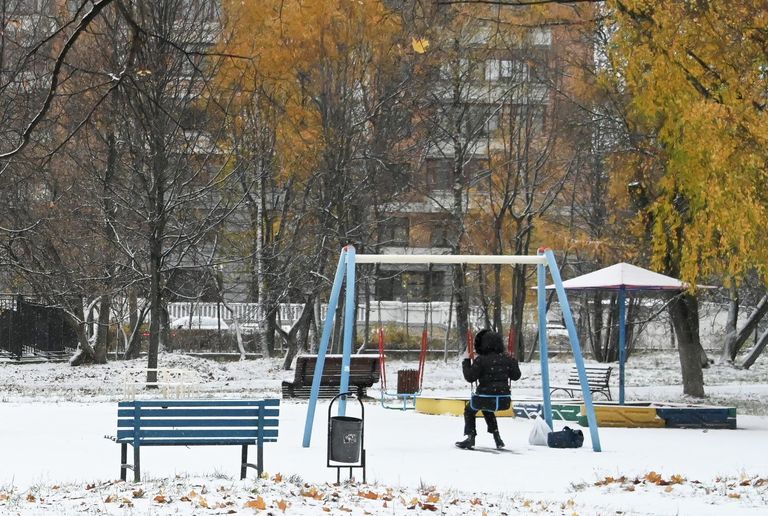 Девочка качается на качелях в заснеженном сквере на Ленинском проспекте в Москве Девочка качается на качелях в заснеженном сквере на Ленинском проспекте в Москве