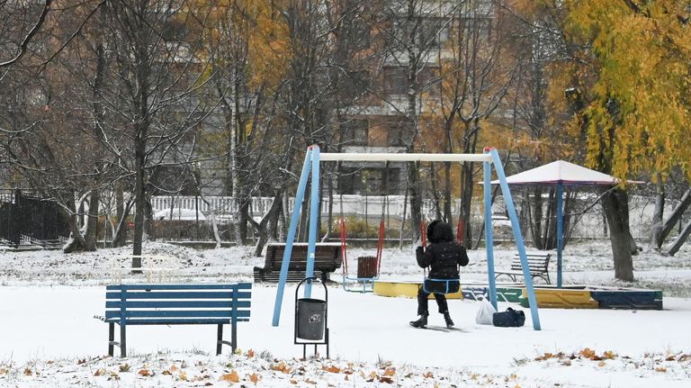 Девочка качается на качелях в заснеженном сквере на Ленинском проспекте в Москве Девочка качается на качелях в заснеженном сквере на Ленинском проспекте в Москве