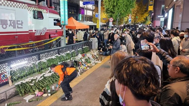 Люди возлагают цветы рядом с местом трагедии, в результате которой погибли 151 человек в Сеуле Люди возлагают цветы рядом с местом трагедии, в результате которой погибли 151 человек в Сеуле