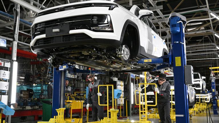 Рабочие за сборкой автомобиля на производственной линии Московского автомобильного завода Москвич
