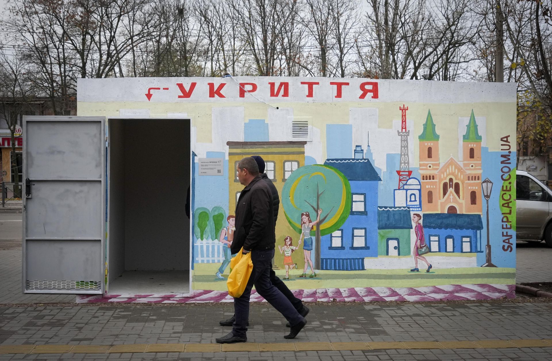 Люди проходят мимо бетонного навеса с надписью Укрытие, установленного на остановке общественного транспорта в Николаеве - РИА Новости, 1920, 29.12.2025