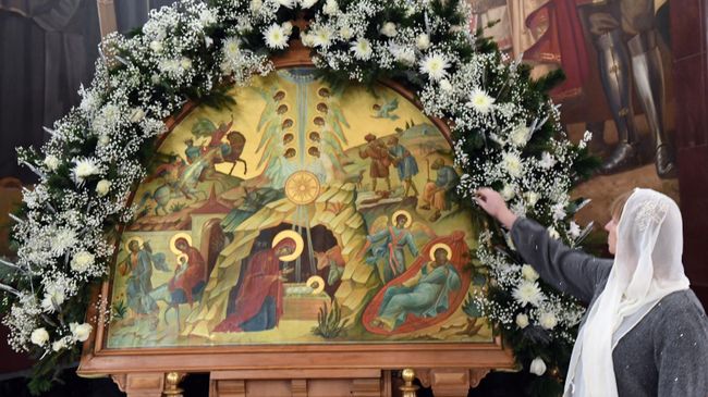 Верующая у иконы Рождество Христово в храме Христа Спасителя в Москве перед началом Рождественского богослужения