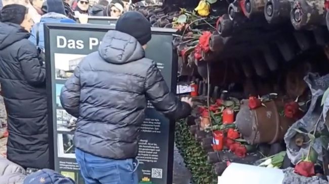 Люди возвращают цветы на танк Т-72 у посольства России в Берлине