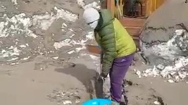 Местная жительница расчищает участок, занесенный пеплом в результате извержения вулкана Шивелуч в Усть-Камчатском районе