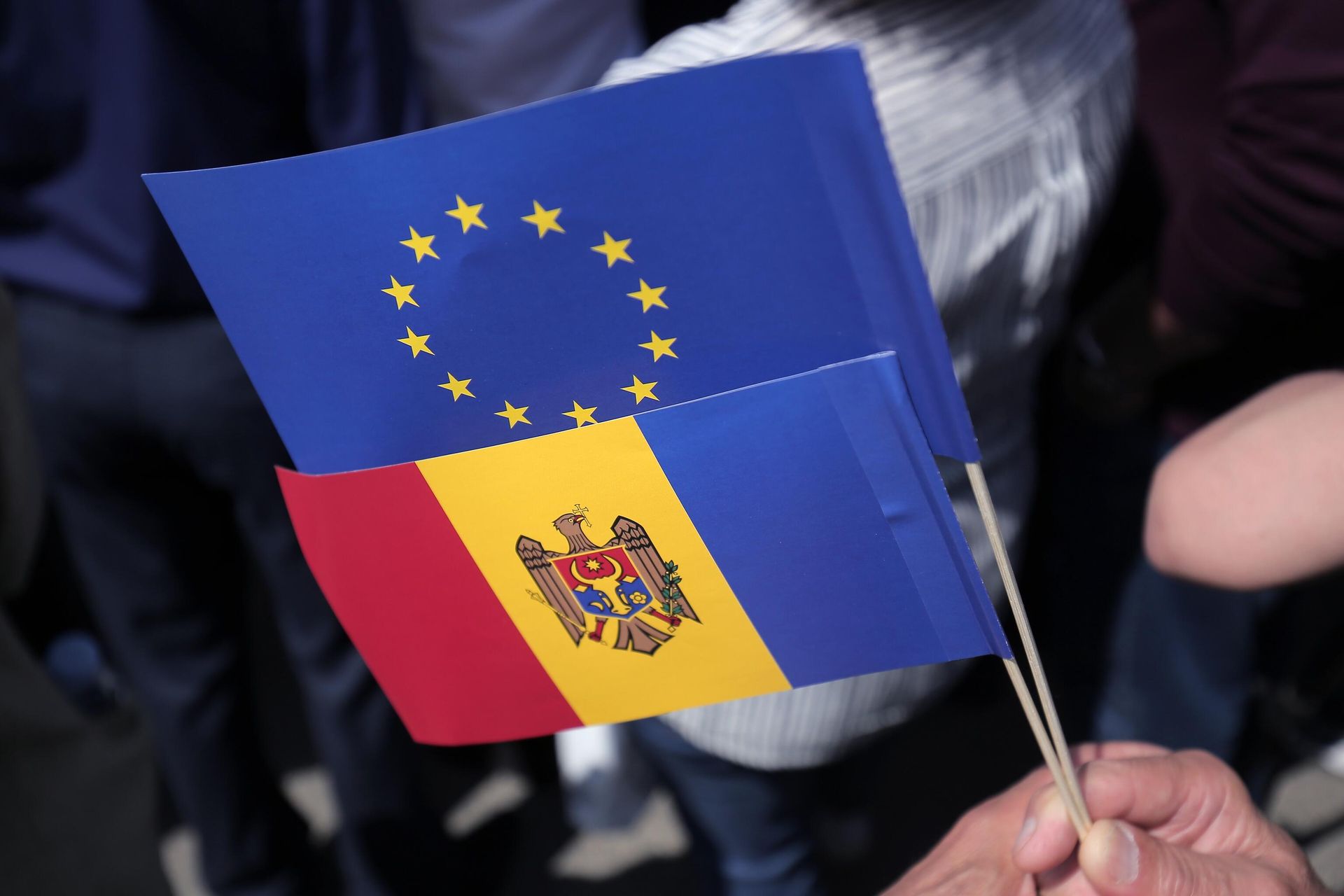 Флаги Молдавии и Евросоюза в руках одного из участников митинга на площади Великого Национального Собрания в Кишиневе Флаги Молдавии и Евросоюза в руках одного из участников митинга на площади Великого Национального Собрания в Кишиневе - РИА Новости, 1920, 17.06.2025