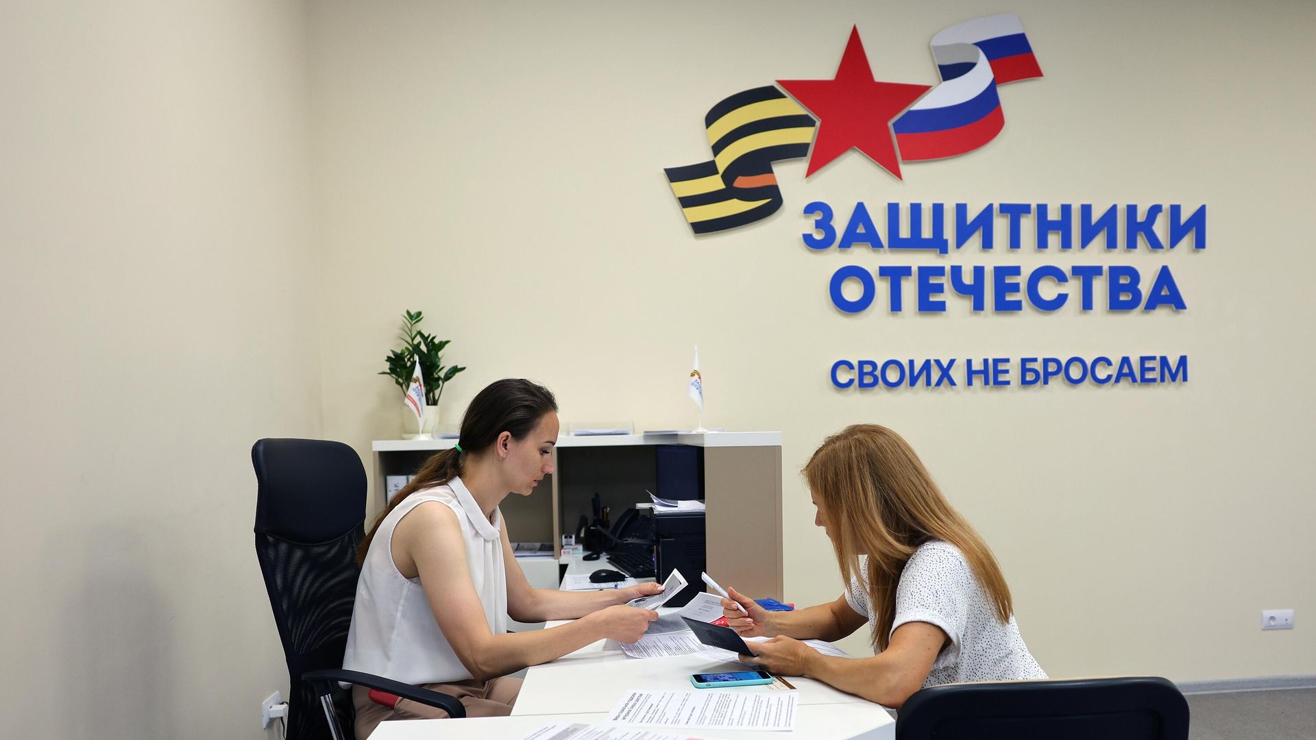 Сотрудница филиала фонда Защитники Отечества общается с посетительницей - РИА Новости, 1920, 25.12.2025
