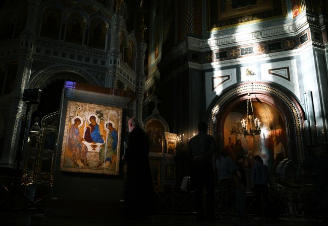 Священнослужитель возле иконы Святая Троица Андрея Рублева в храме Христа Спасителя Священнослужитель возле иконы Святая Троица Андрея Рублева в храме Христа Спасителя