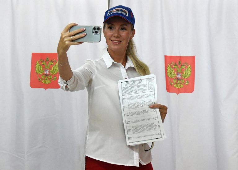 Девушка фотографируется с избирательными бюллетенями на фоне кабинок для голосования на выборах губернатора Красноярского края и депутатов городского совета депутатов Красноярска на избирательном участке No2320 в микрорайоне Академгородок Девушка фотографируется с избирательными бюллетенями на фоне кабинок для голосования на выборах губернатора Красноярского края и депутатов городского совета депутатов Красноярска на избирательном участке No2320 в микрорайоне Академгородок