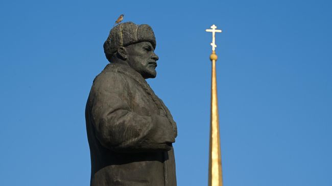 Памятник Ленину в зимней одежде на Красной площади Рыбинска на фоне шпиля Спасо-Преображенского собора, Ярославская область Памятник Ленину в зимней одежде на Красной площади Рыбинска на фоне шпиля Спасо-Преображенского собора, Ярославская область