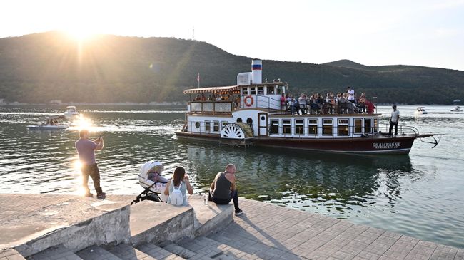 Отдыхающие и прогулочный кораблик на озере Абрау в курортном поселке Абрау-Дюрсо