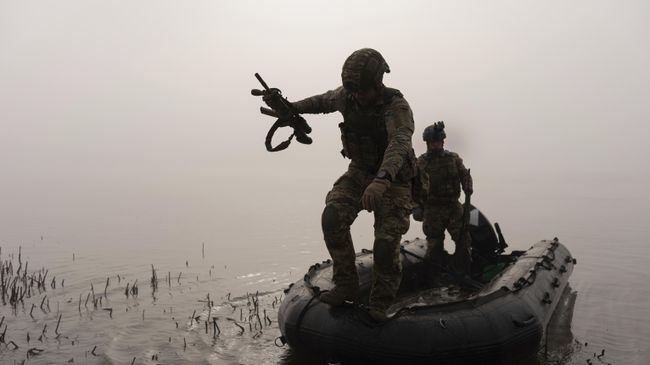 Украинский военнослужащий выпрыгивает из лодки на берег Днепра под Херсоном