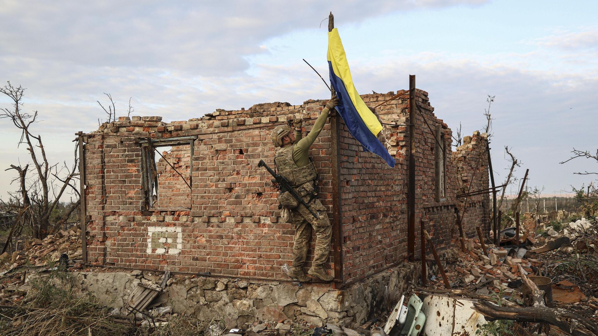 Военнослужащий подразделения ВСУ поднимает украинский флаг над ранее разрушенным зданием - РИА Новости, 1920, 01.10.2025