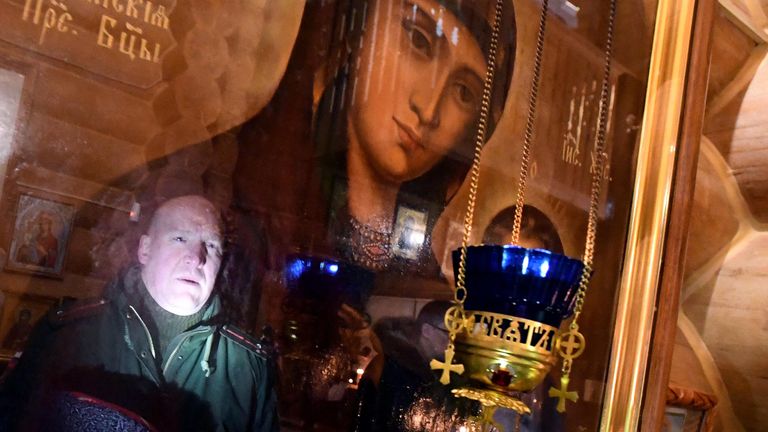 Казак Енисейского казачьего войска отражается в иконе во время Рождественской литургии в деревянной Знаменской православной церкви в Дивногорске Красноярского края Казак Енисейского казачьего войска отражается в иконе во время Рождественской литургии в деревянной Знаменской православной церкви в Дивногорске Красноярского края