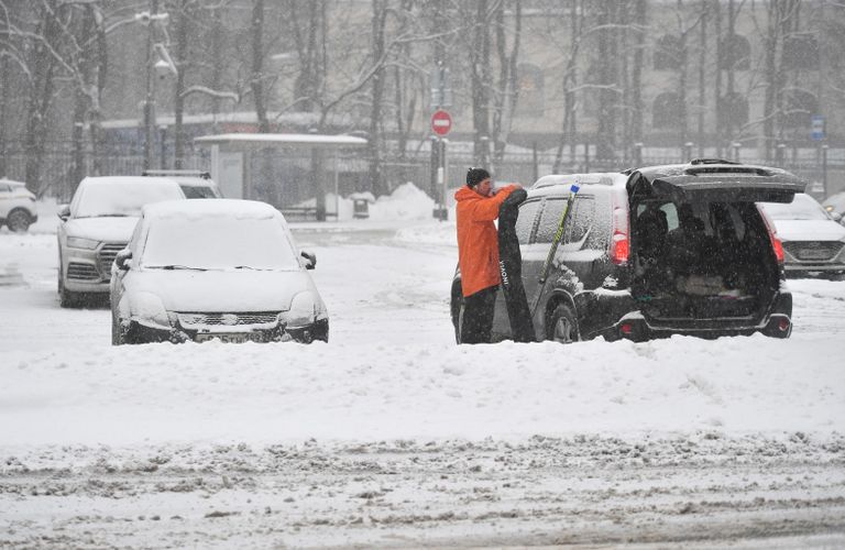 Мужчина стоит возле своей машины во время снегопада в Москве Мужчина стоит возле своей машины во время снегопада в Москве