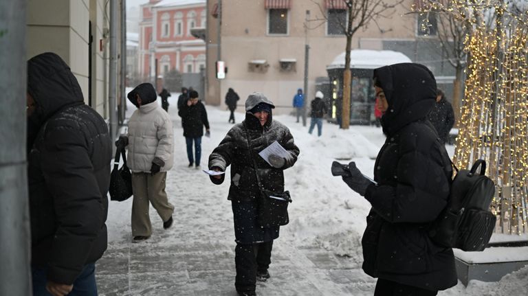 Мужчина раздает листовки во время снегопада в Москве Мужчина раздает листовки во время снегопада в Москве