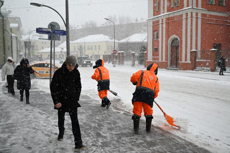 Люди переходят улицу во время снегопада в Москве Люди переходят улицу во время снегопада в Москве