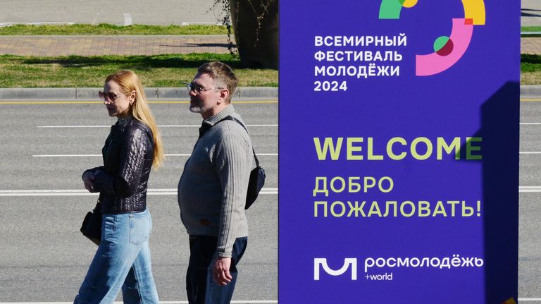 Прохожие у баннера на федеральной территории Сириус во время подготовки ко Всемирному фестивалю молодежи в Сочи Прохожие у баннера на федеральной территории Сириус во время подготовки ко Всемирному фестивалю молодежи в Сочи