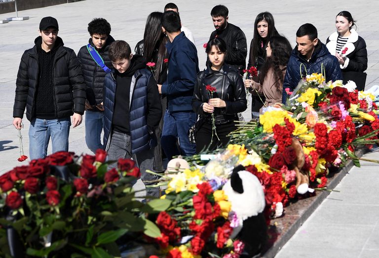Молодые люди возлагают цветы к стихийному мемориалу на площади Ленина в Симферополе во время акции в память о жертвах теракта в подмосковном Крокус Сити Холле