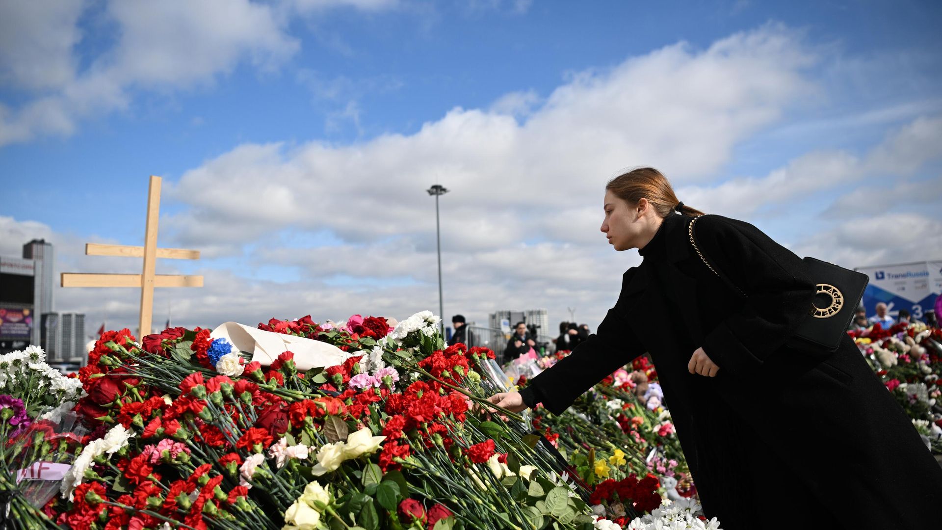 Девушка возлагает цветы на стихийном мемориале у здания концертного зала Крокус Сити Холл, где произошел теракт - РИА Новости, 1920, 25.03.2024