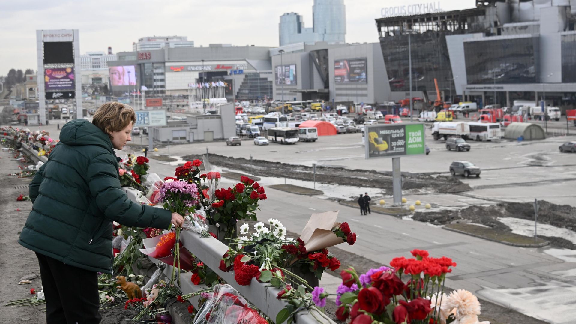 Женщина возлагает цветы у стихийного мемориала вдоль дороги у здания концертного зала Крокус Сити Холл, где произошел теракт - РИА Новости, 1920, 29.03.2024