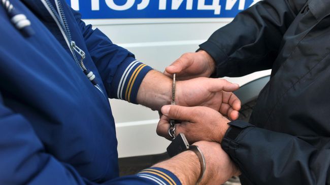 Сотрудник полиции надевает наручники на правонарушителя