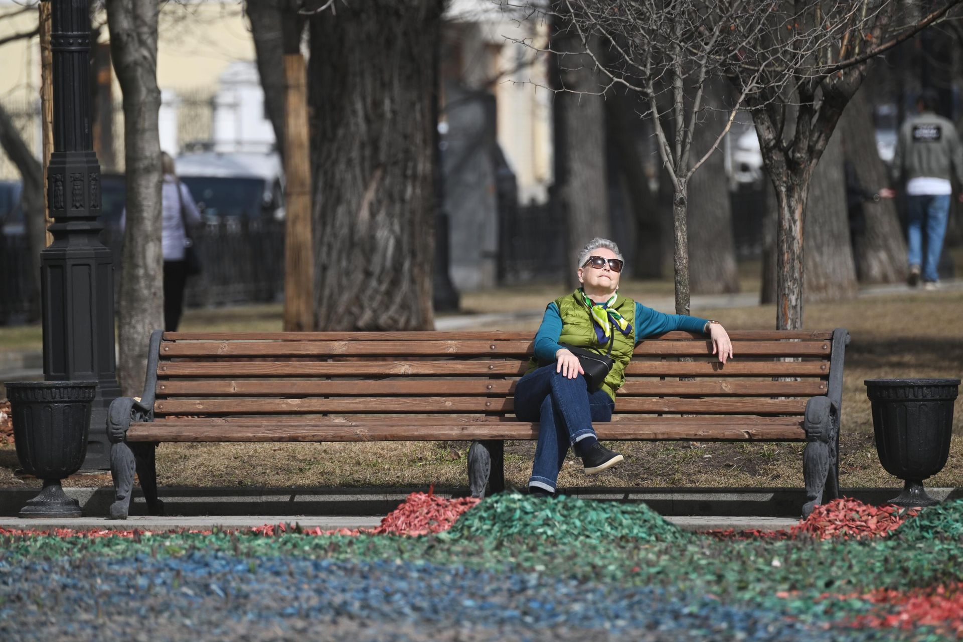 Женщина отдыхает на скамейке во время теплой погоды в одном из парков Москвы - РИА Новости, 1920, 25.03.2026