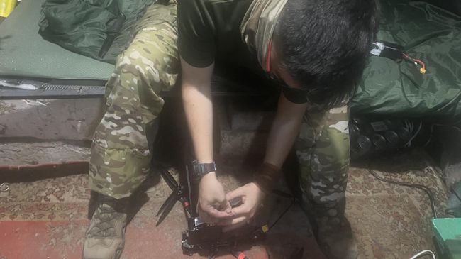 Боец с позывным Корея вставляет батарею в дрон-камикадзе