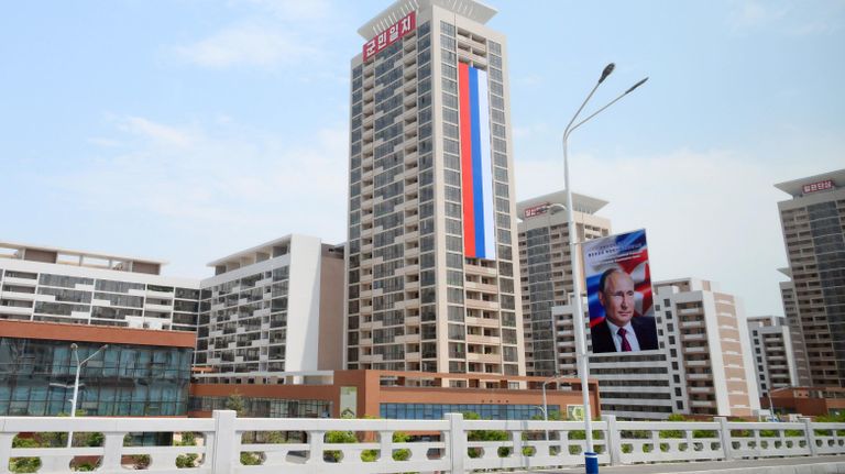 Российский флаг на здании и баннер с портретом президента РФ Владимира Путина на улице в Пхеньяне Российский флаг на здании и баннер с портретом президента РФ Владимира Путина на улице в Пхеньяне