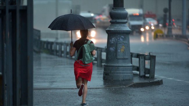Девушка бежит с зонтом во время дождя в Москве