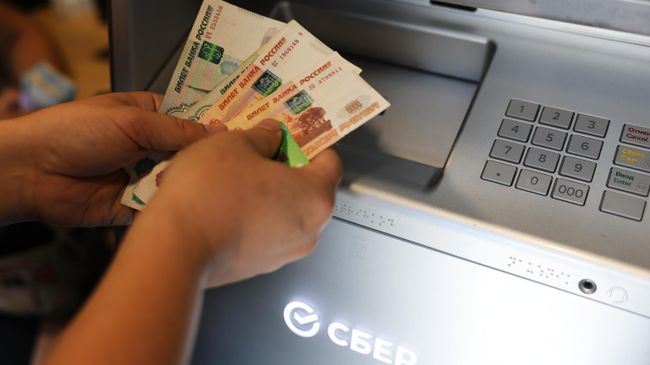 Посетитель снимает наличные в банкомате Посетитель снимает наличные в банкомате