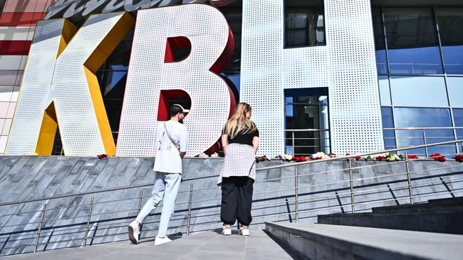 Люди возлагают цветы у молодежного центра Планета КВН в память о ведущем Александре Маслякове